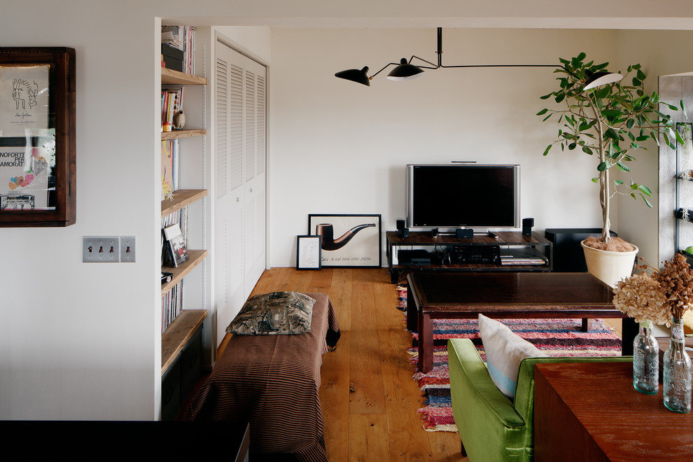 Urban medium tone wood floor and brown floor living room photo in Other with white walls and a tv stand