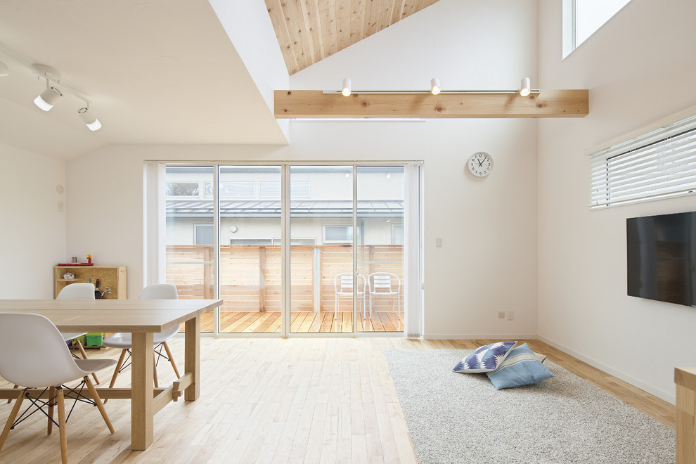 Foto di un soggiorno aperto con pareti bianche, TV a parete e pavimento beige