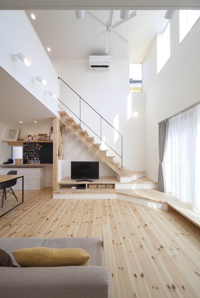 Design ideas for a world-inspired open plan living room in Yokohama with white walls, light hardwood flooring, a freestanding tv and brown floors.