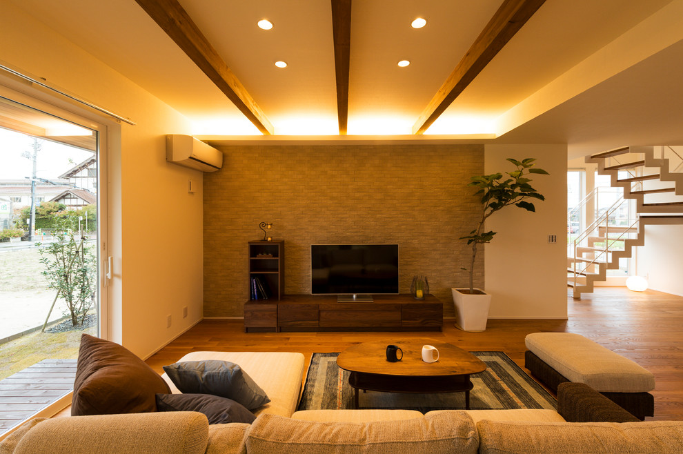 Cette photo montre un salon asiatique ouvert avec un mur multicolore, un sol en bois brun, un téléviseur indépendant et un sol marron.