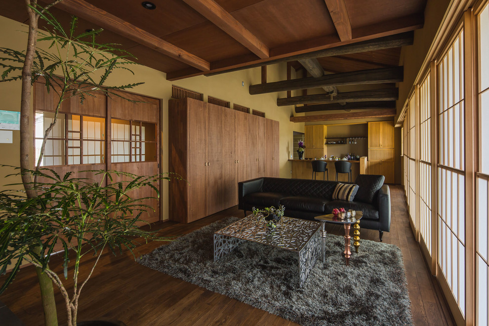 Aménagement d'un salon asiatique ouvert avec un mur marron, parquet foncé et un sol marron.