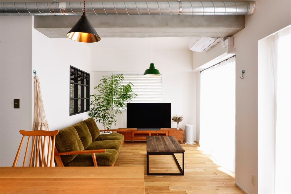 Offenes Skandinavisches Wohnzimmer mit weißer Wandfarbe, braunem Holzboden, freistehendem TV und braunem Boden