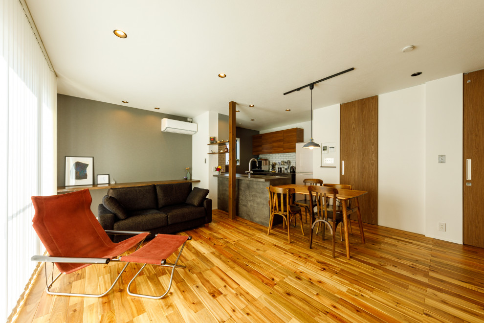 Ejemplo de salón abierto industrial con paredes blancas, suelo de madera clara y suelo marrón