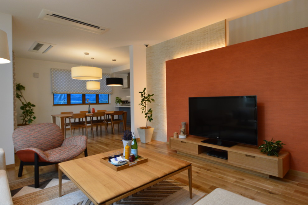 Esempio di un grande soggiorno minimalista aperto con pareti arancioni, pavimento in legno massello medio, nessun camino e TV autoportante