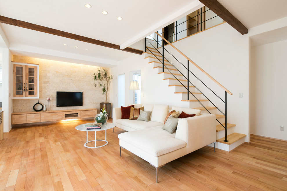 Aménagement d'un grand salon contemporain ouvert avec un mur blanc, un téléviseur encastré et un sol marron.