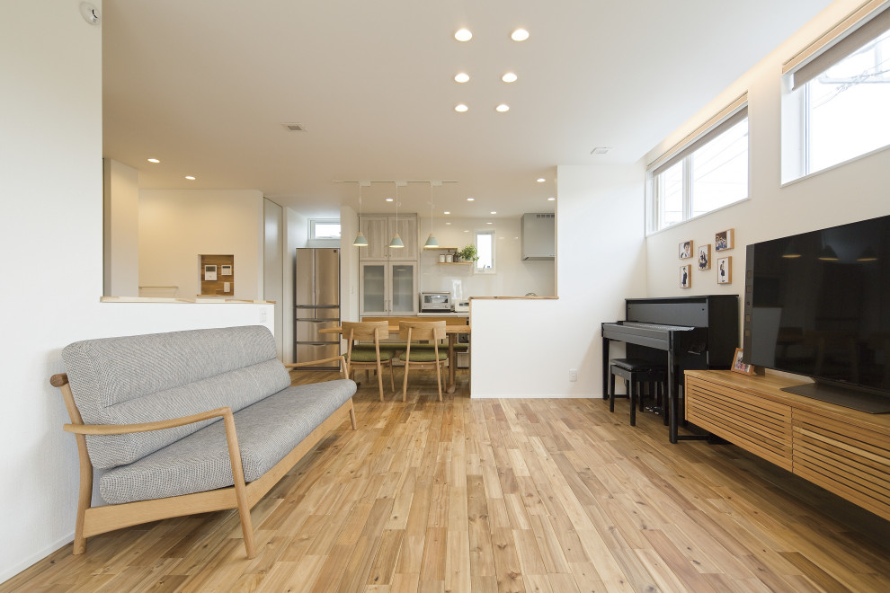Modelo de salón para visitas abierto moderno de tamaño medio con paredes blancas, suelo de madera clara, televisor independiente, suelo marrón, papel pintado y papel pintado