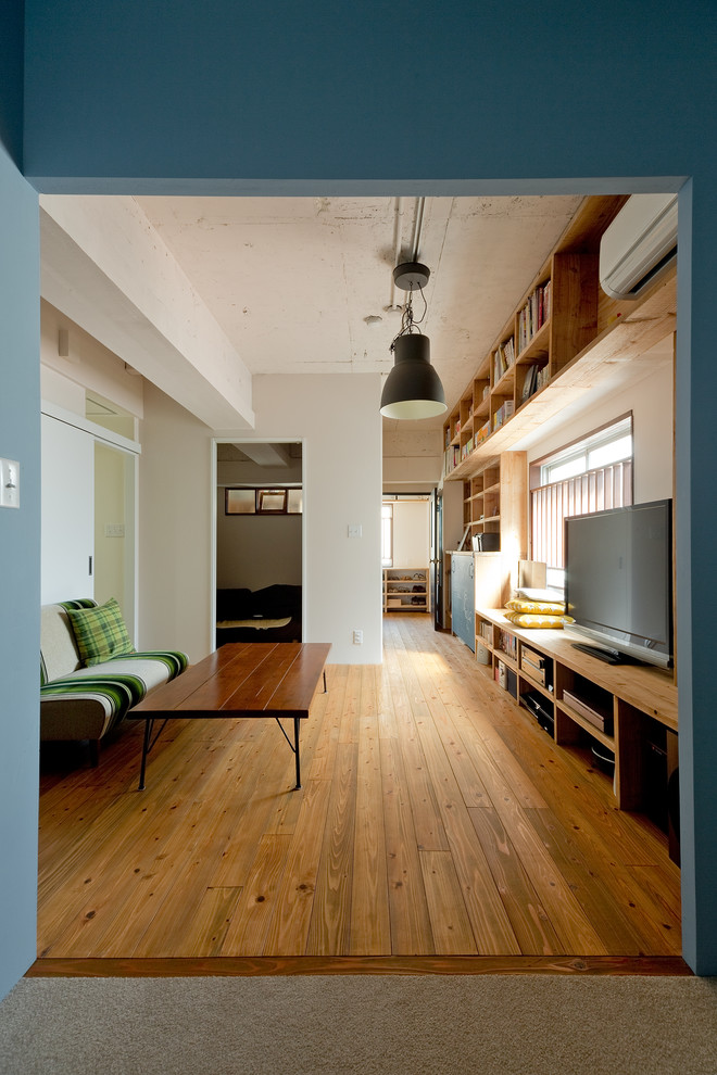Asiatisches Wohnzimmer mit braunem Holzboden, braunem Boden, weißer Wandfarbe und freistehendem TV in Osaka