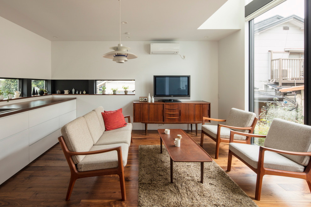 Idéer för minimalistiska vardagsrum, med vita väggar, mellanmörkt trägolv och en fristående TV