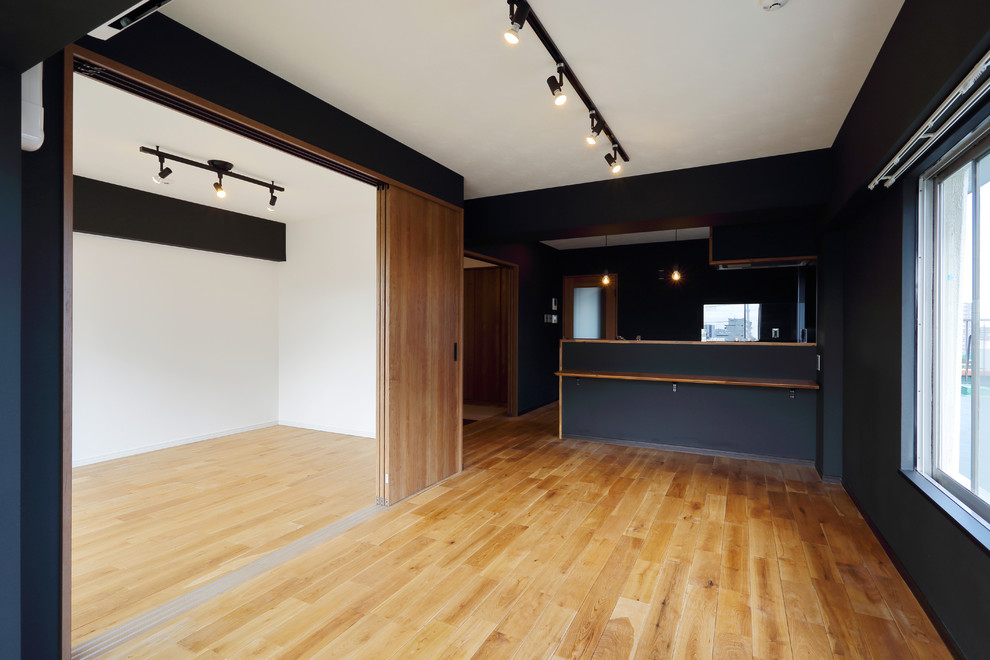 Foto di un soggiorno minimalista di medie dimensioni e aperto con pareti nere, pavimento in legno massello medio, nessun camino e pavimento marrone