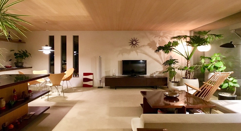 Aménagement d'un salon rétro ouvert avec un mur blanc, un téléviseur indépendant et un sol beige.