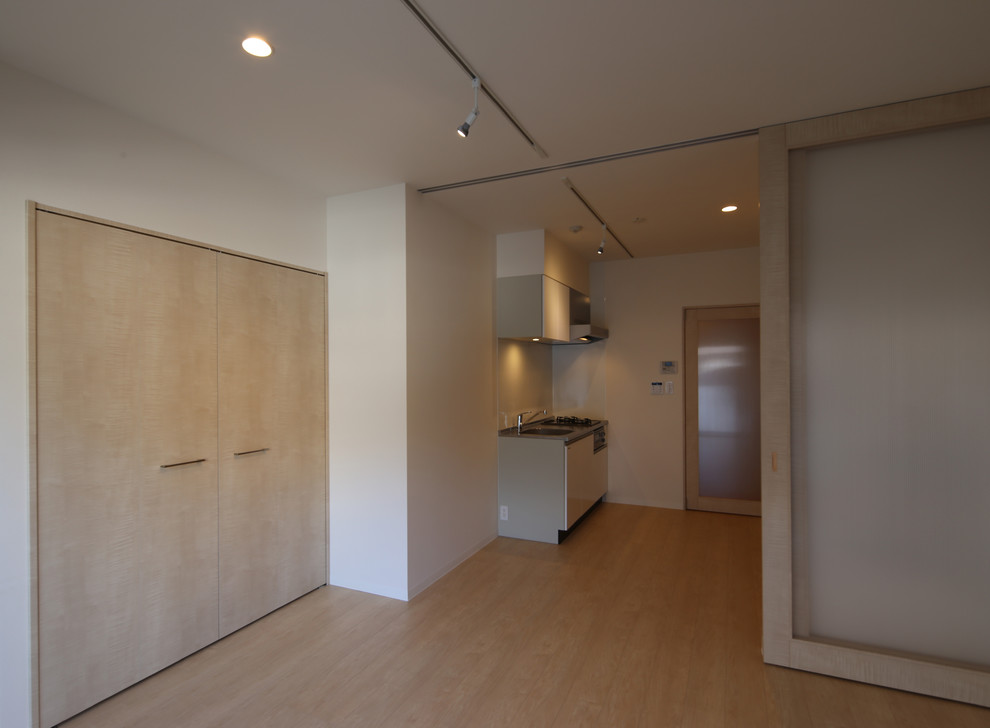 Mittelgroßes, Offenes Modernes Wohnzimmer ohne Kamin mit Hausbar, weißer Wandfarbe, hellem Holzboden, verputzter Kaminumrandung, freistehendem TV und beigem Boden in Tokio