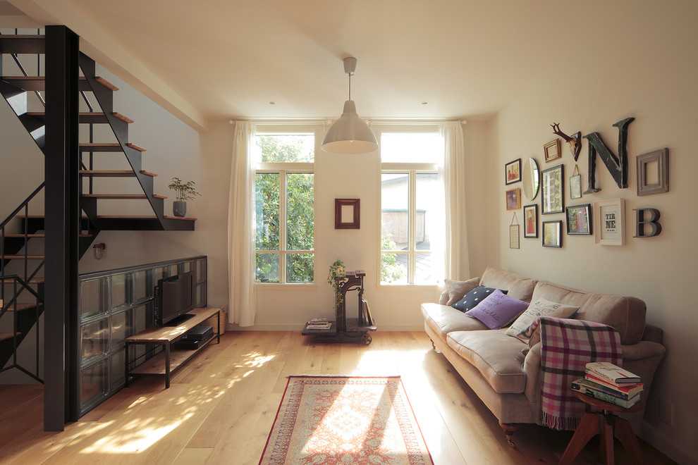 Foto på ett eklektiskt allrum med öppen planlösning, med vita väggar, ljust trägolv, en fristående TV och beiget golv