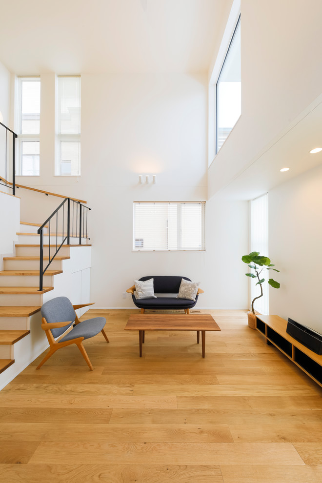 Стильный дизайн: гостиная комната в скандинавском стиле с белыми стенами, паркетным полом среднего тона и коричневым полом - последний тренд