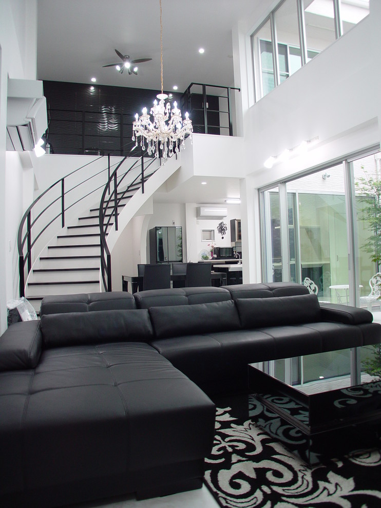 Exemple d'un salon moderne ouvert avec un mur blanc et canapé noir.