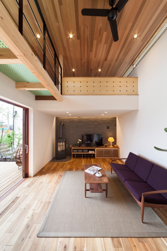 Kleines Modernes Wohnzimmer mit weißer Wandfarbe, Kaminofen, freistehendem TV und braunem Boden in Sonstige