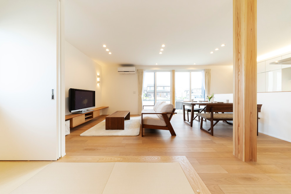 Immagine di un soggiorno minimalista aperto con pareti bianche, pavimento in legno massello medio, nessun camino, TV autoportante e pavimento marrone