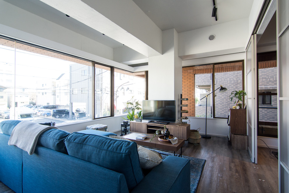 Ejemplo de salón abierto asiático con paredes blancas, suelo de madera oscura, televisor independiente y suelo marrón