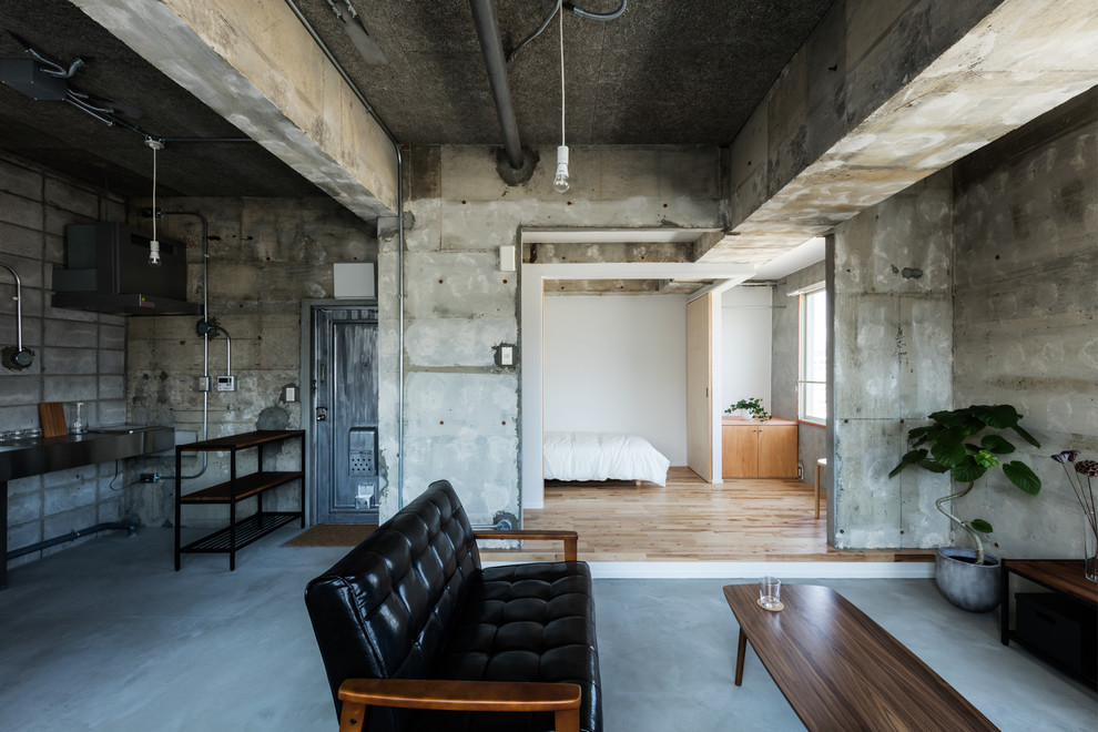 Cette image montre un salon urbain ouvert avec un mur gris, sol en béton ciré et un sol gris.
