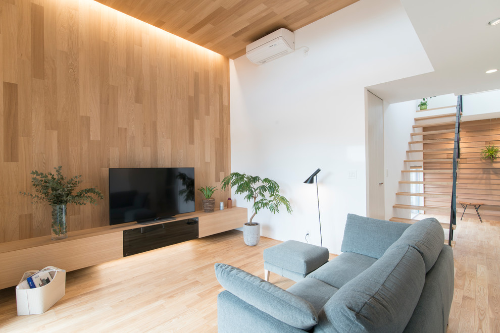 Ejemplo de salón minimalista con paredes multicolor, suelo de madera clara, televisor independiente y suelo beige