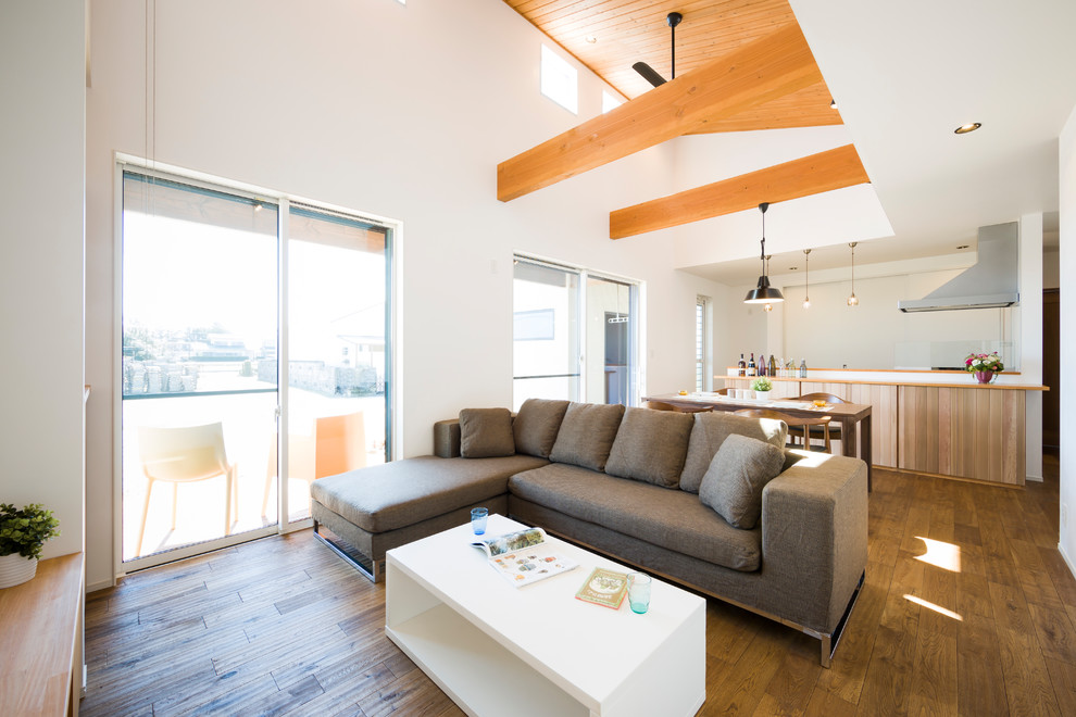 Modern living room with white walls, dark hardwood flooring and brown floors.