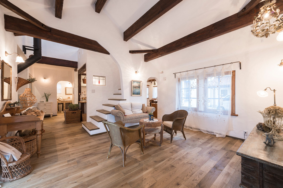 Cette photo montre un salon méditerranéen de taille moyenne et fermé avec un mur blanc, parquet clair, un poêle à bois, un manteau de cheminée en brique et un sol marron.
