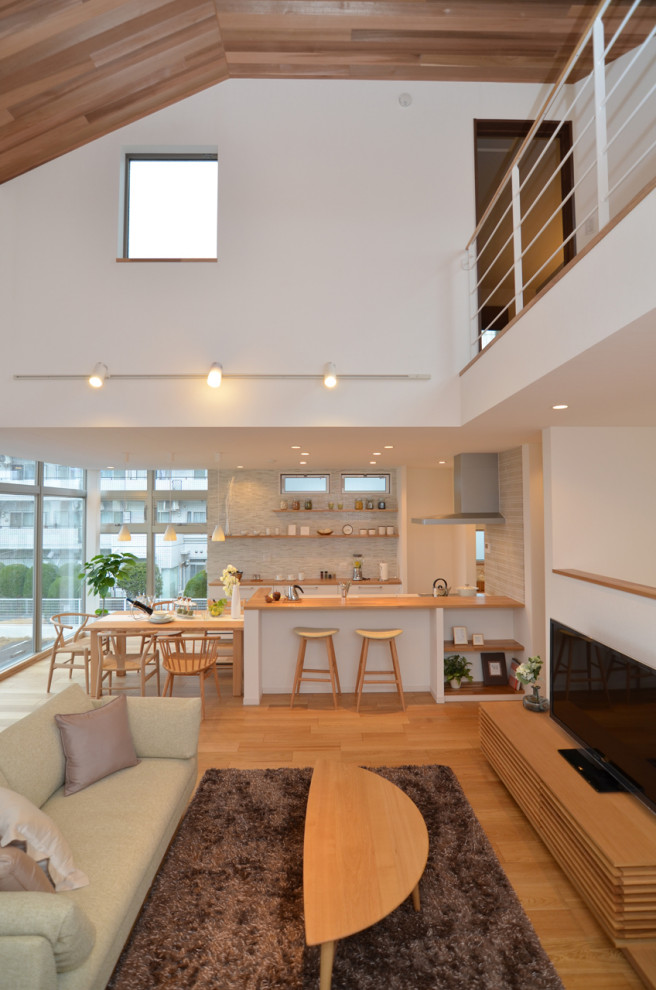Bild på ett stort minimalistiskt allrum med öppen planlösning, med vita väggar, ljust trägolv, en fristående TV och brunt golv
