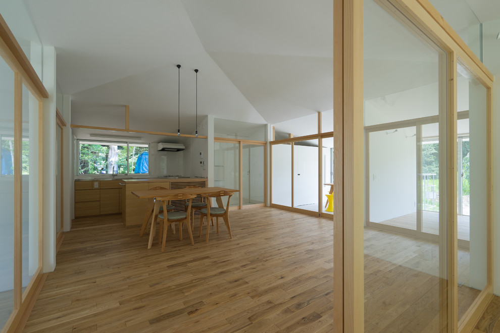 Offenes Modernes Wohnzimmer mit braunem Holzboden und weißer Wandfarbe in Sonstige