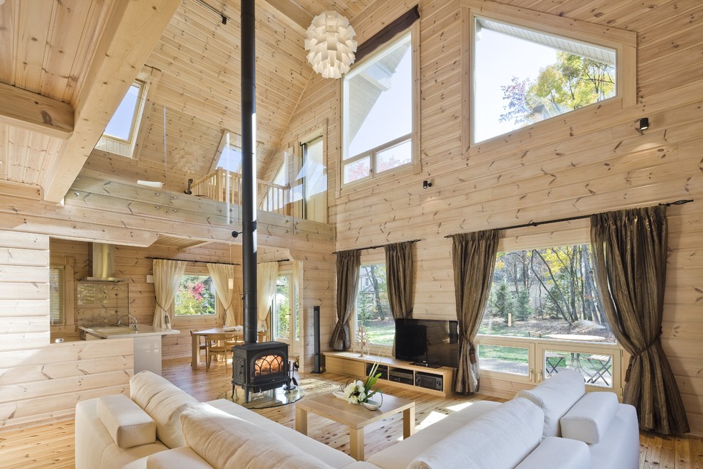Esempio di un grande soggiorno rustico aperto con parquet chiaro, stufa a legna, TV autoportante, pareti beige e cornice del camino in legno