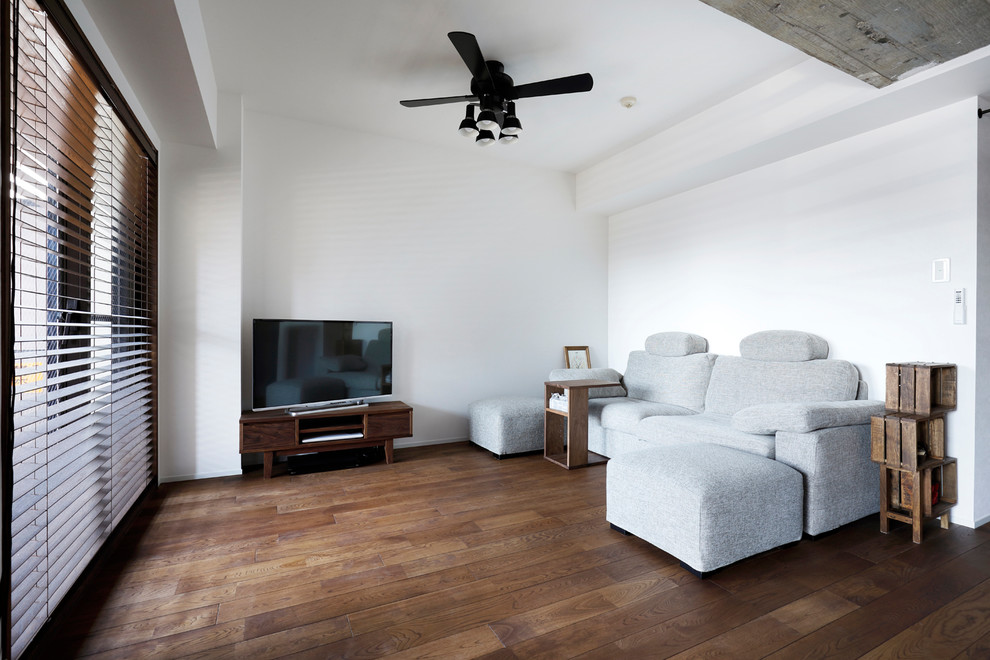 Foto di un soggiorno etnico con pareti bianche, parquet scuro, TV autoportante e pavimento marrone