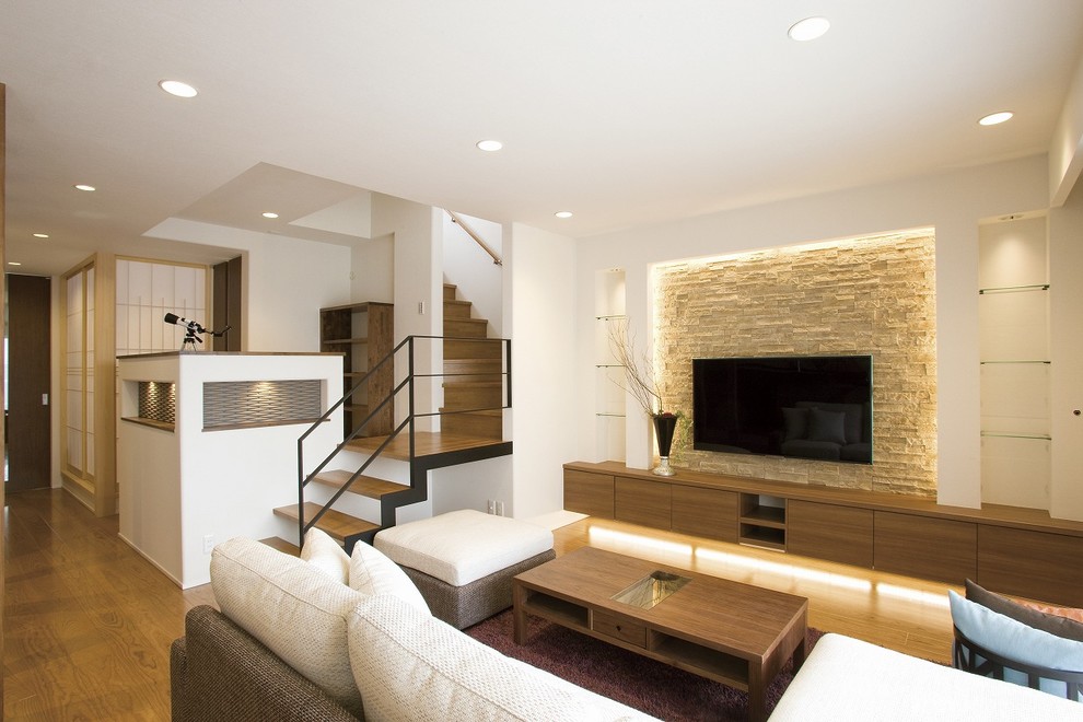 Inspiration pour un salon design avec un mur multicolore, un sol en bois brun, un téléviseur fixé au mur et un sol marron.