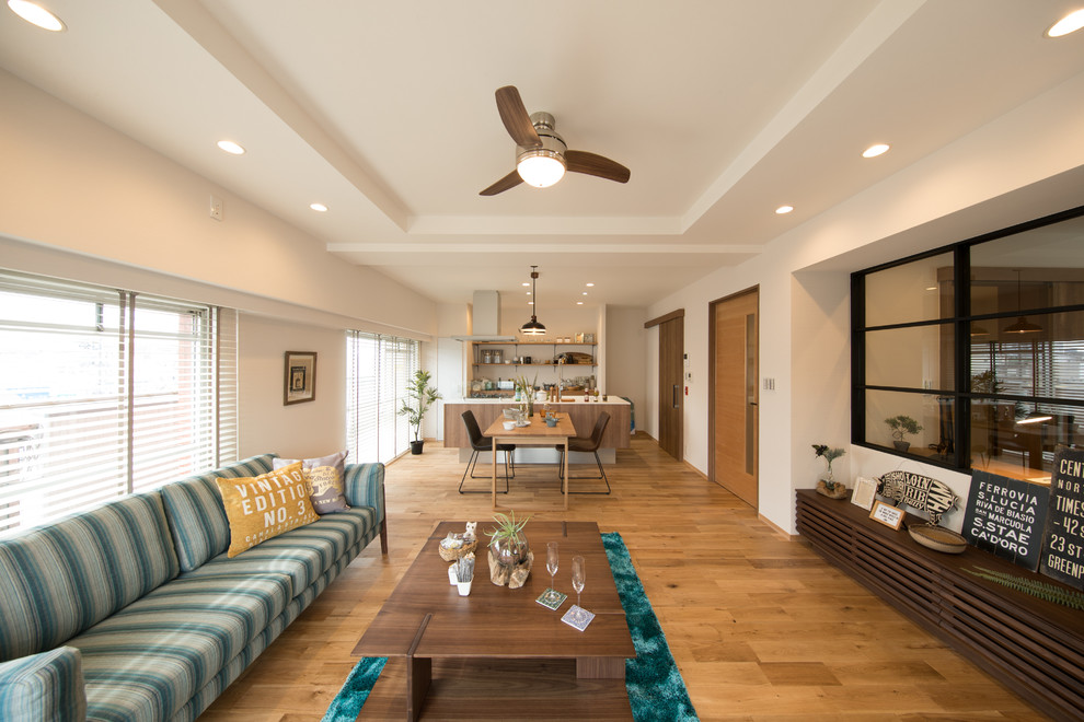 Esempio di un soggiorno stile marino di medie dimensioni e aperto con pareti bianche, pavimento in legno massello medio e pavimento marrone