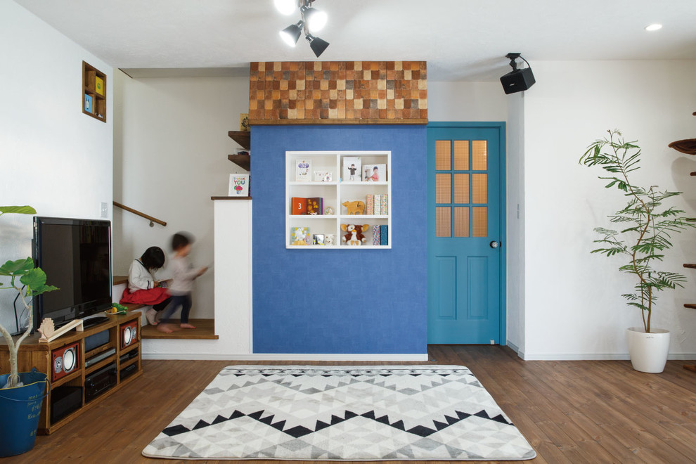 Skandinavisches Wohnzimmer mit bunten Wänden, braunem Holzboden, freistehendem TV und braunem Boden in Sonstige