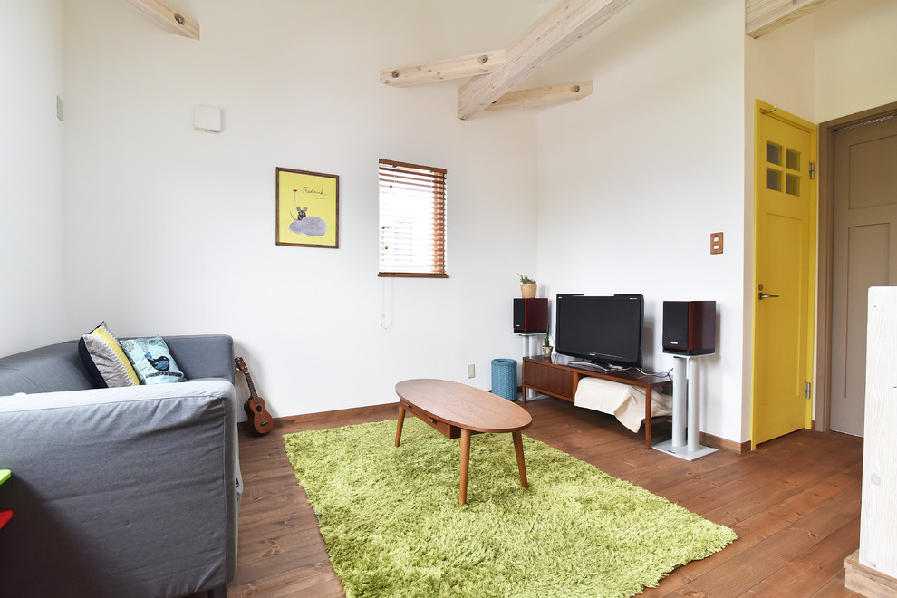 Offenes Landhausstil Wohnzimmer mit weißer Wandfarbe, dunklem Holzboden, freistehendem TV und braunem Boden in Sonstige