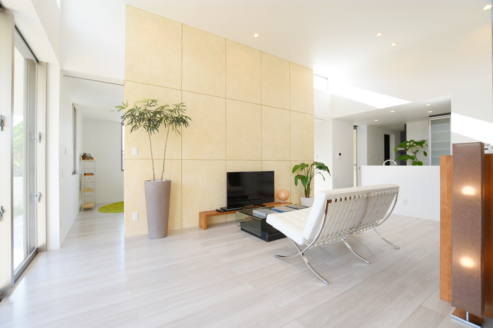 Источник вдохновения для домашнего уюта: открытая гостиная комната в стиле модернизм с желтыми стенами, полом из фанеры, отдельно стоящим телевизором и белым полом без камина