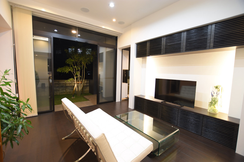 Modern inredning av ett allrum med öppen planlösning, med vita väggar, plywoodgolv, en fristående TV och svart golv
