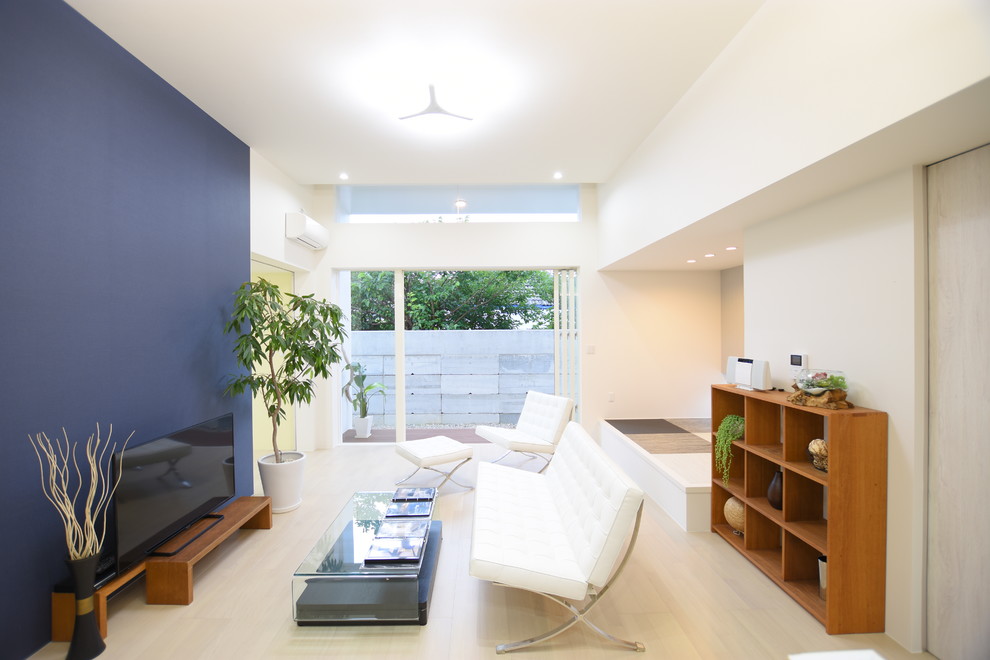 Imagen de salón abierto de estilo zen sin chimenea con paredes azules, televisor independiente, suelo de madera clara y suelo beige