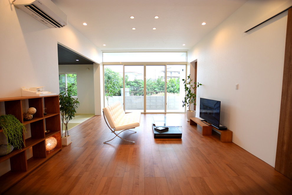 Exempel på ett modernt allrum med öppen planlösning, med vita väggar, plywoodgolv, en fristående TV och brunt golv
