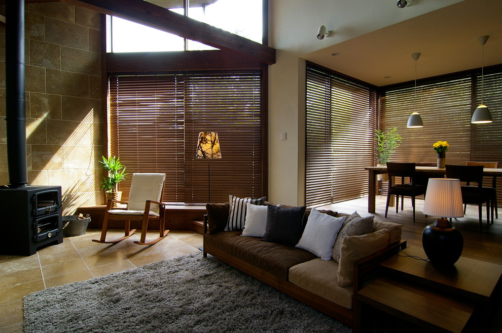 Пример оригинального дизайна: открытая гостиная комната в стиле ретро с белыми стенами, полом из травертина, печью-буржуйкой, фасадом камина из камня и бежевым полом