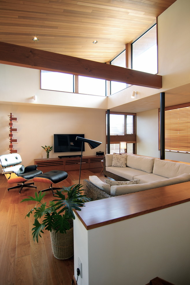 Offenes Mid-Century Wohnzimmer ohne Kamin mit braunem Holzboden, TV-Wand, braunem Boden und weißer Wandfarbe in Sonstige