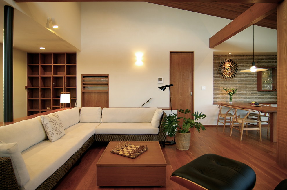 Offenes Retro Wohnzimmer ohne Kamin mit braunem Holzboden, TV-Wand, braunem Boden und weißer Wandfarbe in Sonstige