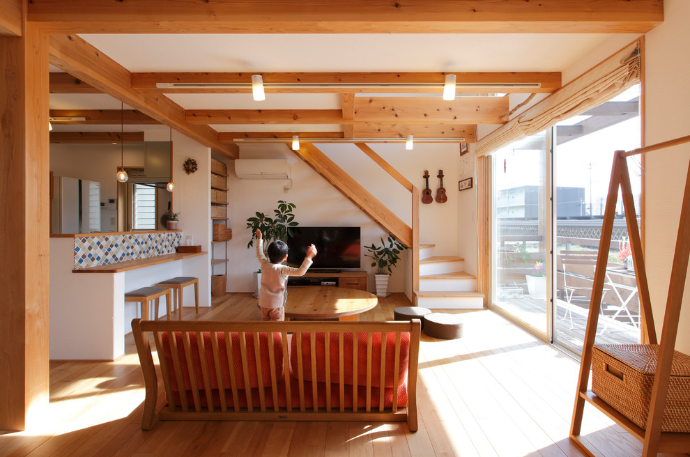 This is an example of a small world-inspired open plan living room in Other with white walls, a freestanding tv, medium hardwood flooring and no fireplace.