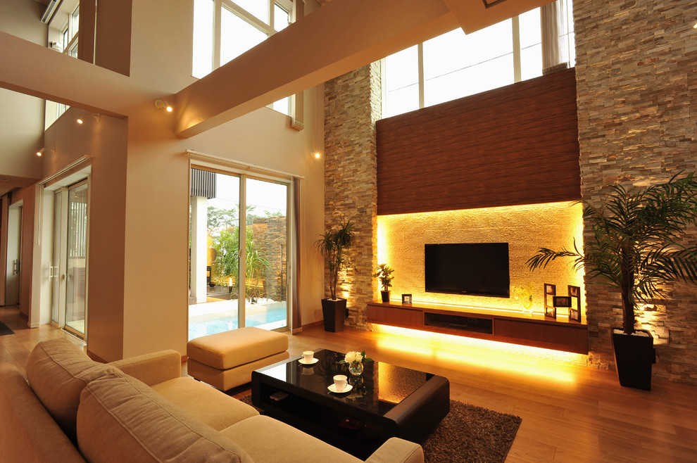 Offenes Modernes Wohnzimmer ohne Kamin mit beiger Wandfarbe, hellem Holzboden, TV-Wand und beigem Boden in Sonstige