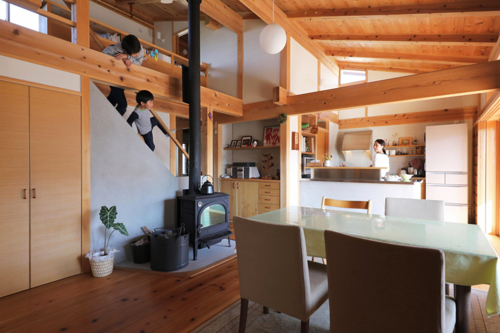 Ejemplo de salón abierto de estilo zen de tamaño medio sin televisor con suelo de madera en tonos medios, estufa de leña y marco de chimenea de hormigón