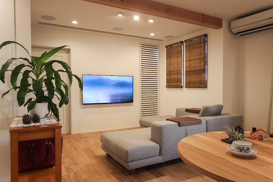 Exempel på ett nordiskt vardagsrum, med vita väggar, mellanmörkt trägolv och en väggmonterad TV