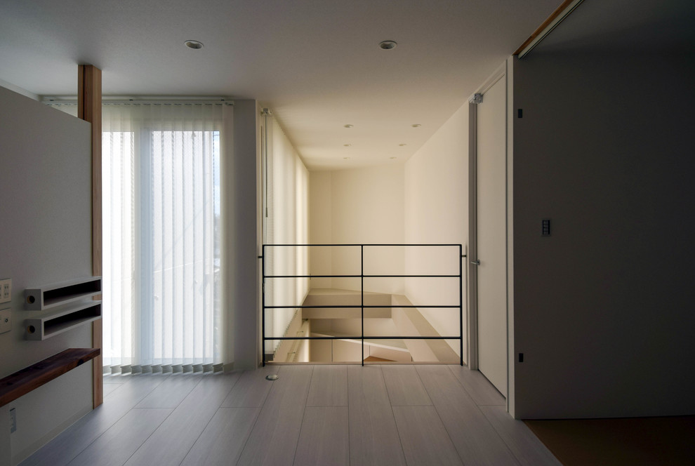 Cette photo montre un grand salon moderne ouvert avec un mur blanc, un téléviseur fixé au mur et un sol blanc.