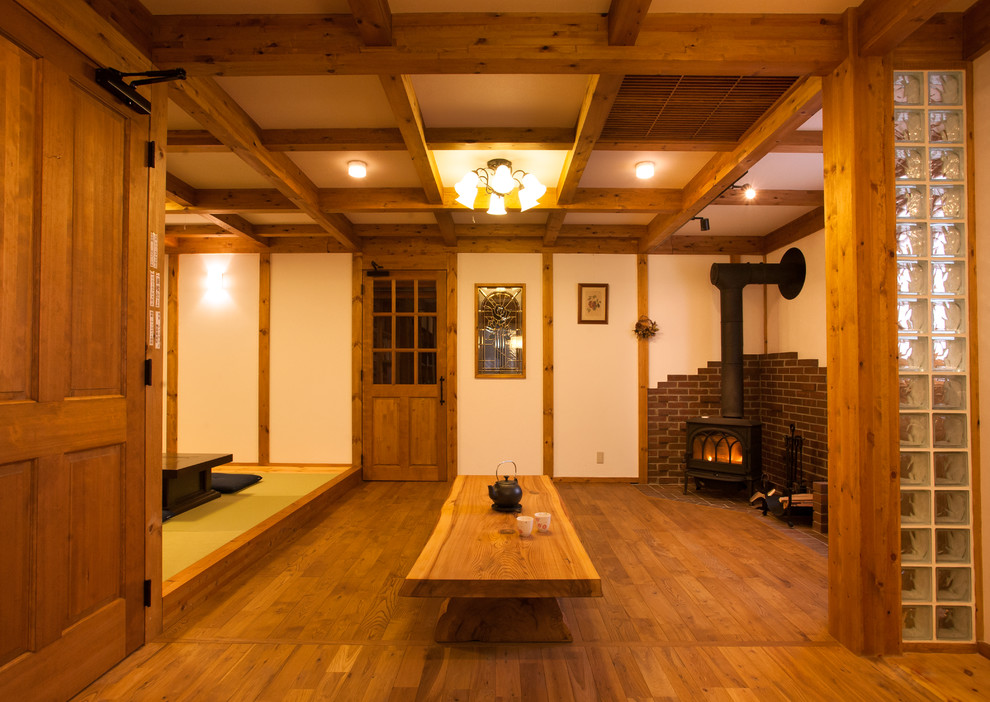 Imagen de salón abierto de estilo zen con paredes blancas, suelo de madera en tonos medios, estufa de leña y marco de chimenea de ladrillo
