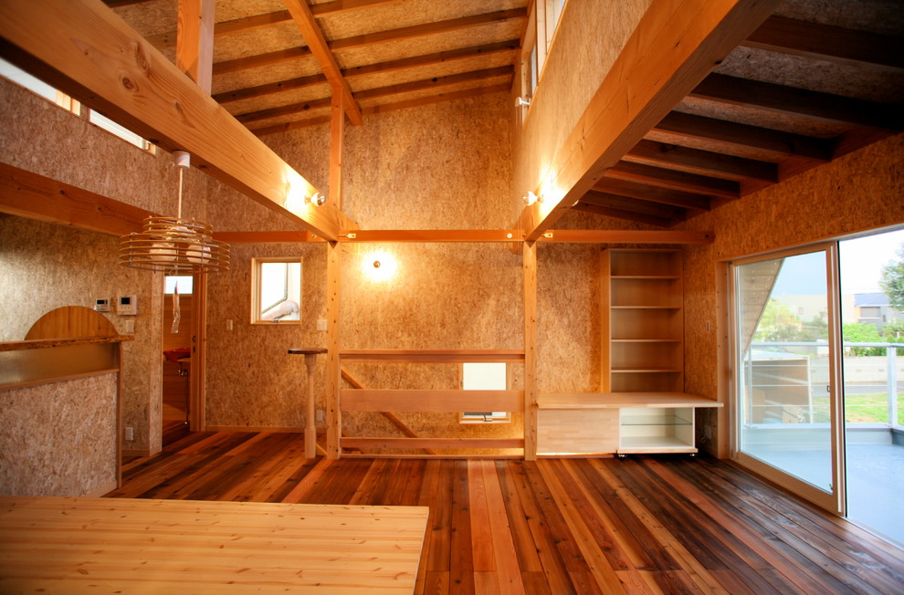 Asiatisk inredning av ett litet allrum med öppen planlösning, med beige väggar, mörkt trägolv, en fristående TV och brunt golv