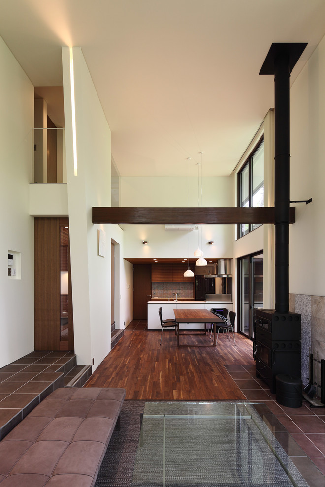 Идея дизайна: гостиная комната среднего размера в стиле модернизм с белыми стенами, темным паркетным полом, печью-буржуйкой, фасадом камина из плитки и коричневым полом