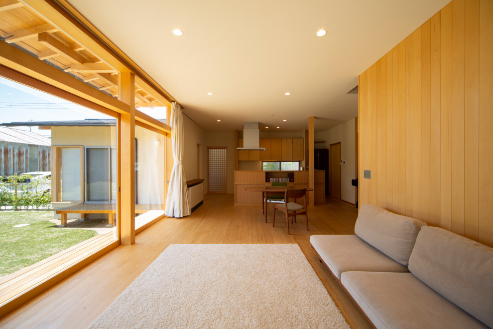 Imagen de salón abierto asiático grande con paredes blancas, suelo de madera en tonos medios y suelo beige