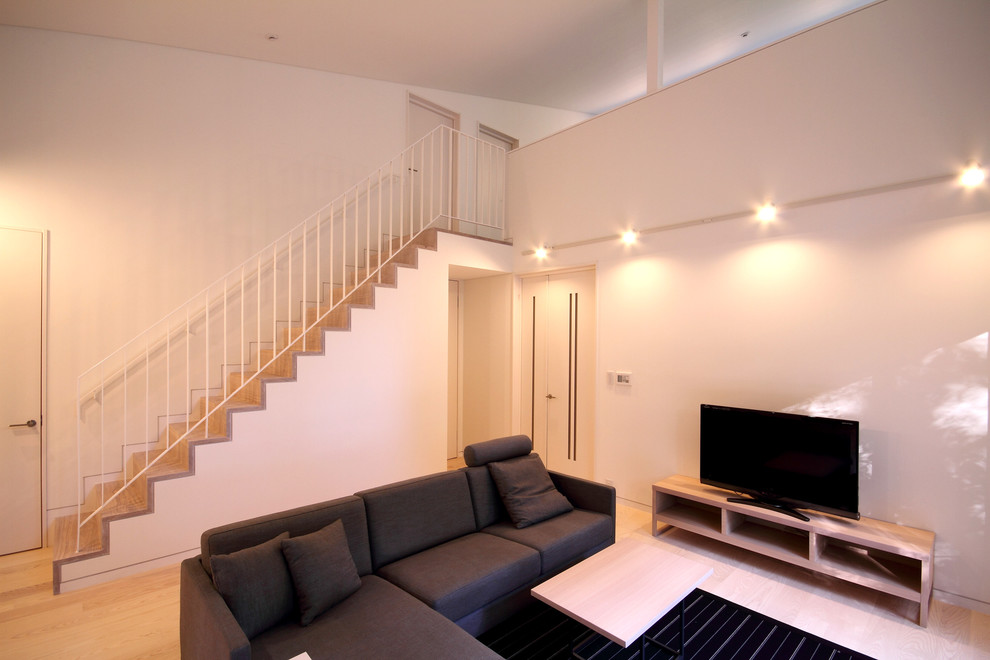 Пример оригинального дизайна: изолированная гостиная комната среднего размера в стиле модернизм с белыми стенами, деревянным полом, двусторонним камином, фасадом камина из камня, отдельно стоящим телевизором и бежевым полом